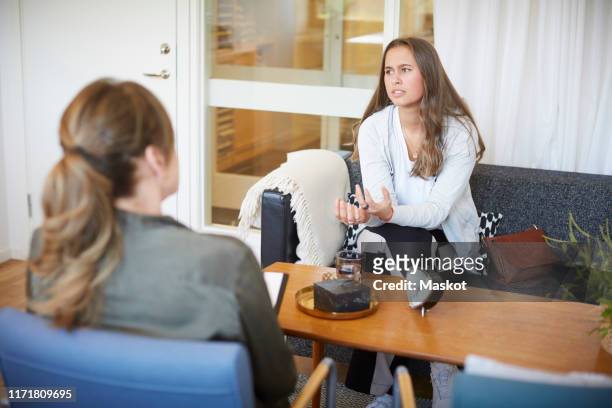 teenage girl discussing problems with female therapist at community center - alternative therapy stock pictures, royalty-free photos & images