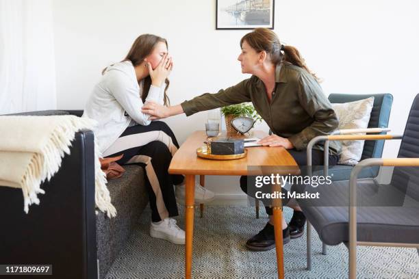 female therapist consoling teenage patient during session at workshop - teen mental illness stock pictures, royalty-free photos & images