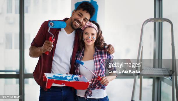 young happy couple painting their new home. - paint tray stock pictures, royalty-free photos & images