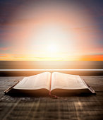 Close up of open Bible, with dramatic light. Wood table with sun rays coming through window. Christian image