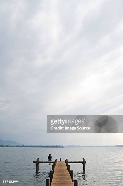woman sitting on a jetty - cloudy stockfoto's en -beelden