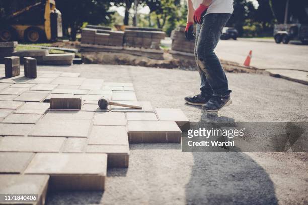 junger mann installiert pflastersteine für eine neue einfahrt - paving stone stock-fotos und bilder