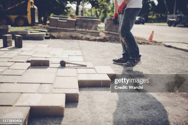 jonge man het installeren van stoep stenen voor een nieuwe oprit - installation stockfoto's en -beelden