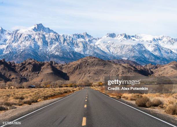 highway heading toward sierra nevada mountains covered by snow. california, usa - sierra nevada da califórnia imagens e fotografias de stock