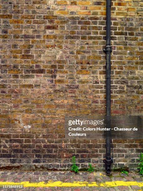london weathered brick wall, pipe and yellow line - rinnstein stock-fotos und bilder