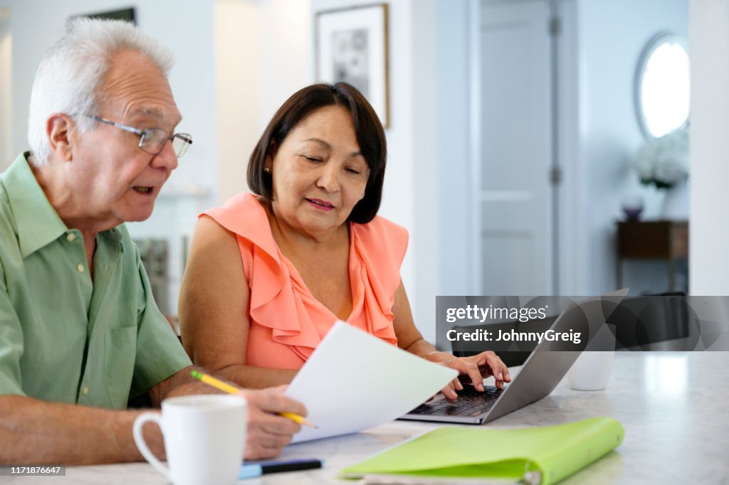 Hispanic senior couple using laptop to organize financial planning