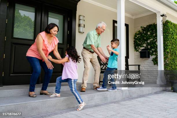 hispanic grandparents welcoming home their grandchildren - family smiling at front door stock pictures, royalty-free photos & images