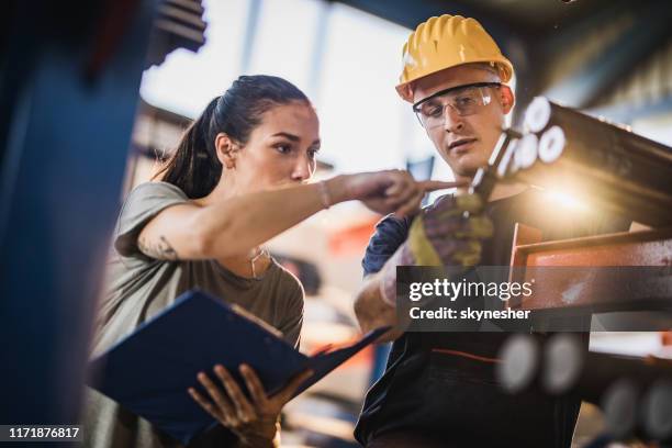 female manager and manual worker measuring steel in industrial building. - foundry stock pictures, royalty-free photos & images