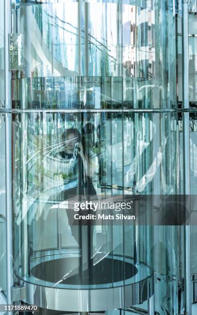 woman inside a modern glass elevator and using phone - switzerland business stock pictures, royalty-free photos & images