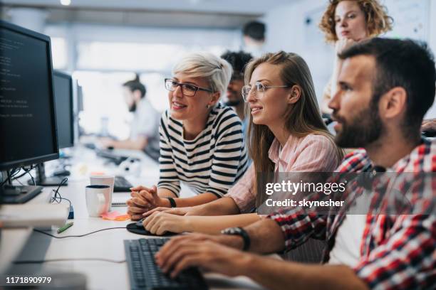 team of young computer programmers cooperating while working on desktop pc in the office. - software engineers stock pictures, royalty-free photos & images