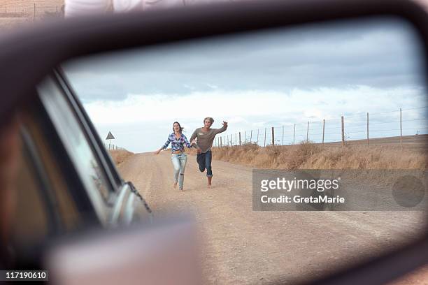 couple running behind car - carro de corrida fotografías e imágenes de stock