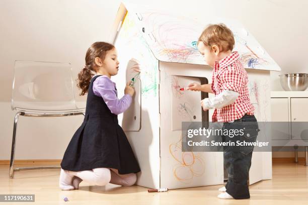 boy and girl painting cardboard house - cardboard house stock pictures, royalty-free photos & images