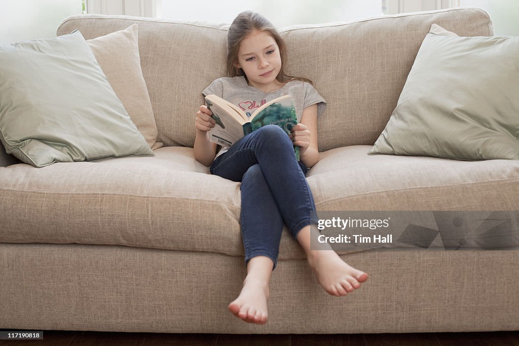 Giovane ragazza lettura libro sul divano