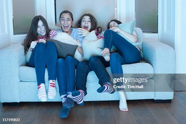 teenage girls watching tv on sofa - girls sleepover stock-fotos und bilder