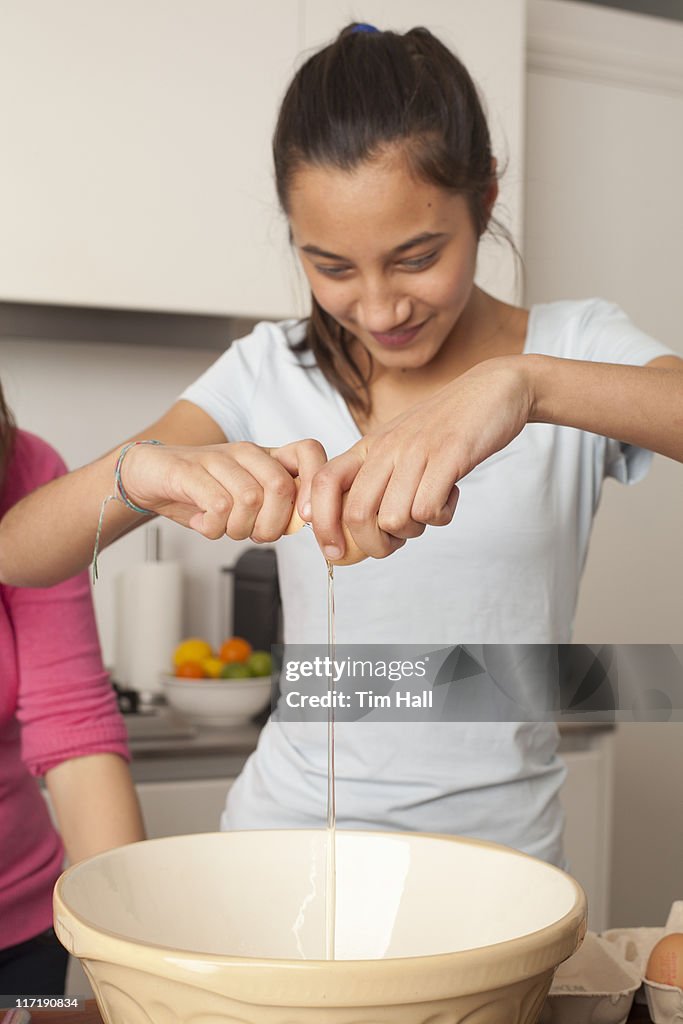 Girl , breaking an egg in kitchen