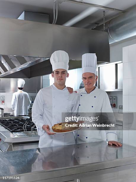 köche apprentice mit hausgemachten kuchen - kochlehrling stock-fotos und bilder