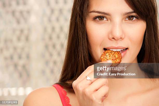 woman biting a biscuit half smiling - biscuit france stock pictures, royalty-free photos & images