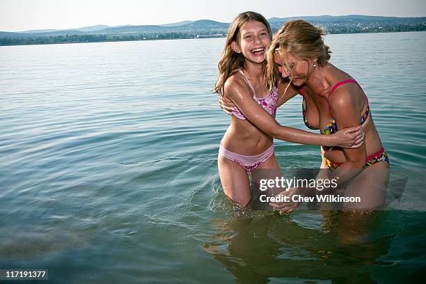 mother and daughter laughing in lake - tween girls swimwear 個照片及圖片檔