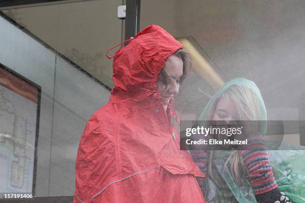 2 women at bus stop in the rain - rain poncho stockfoto's en -beelden