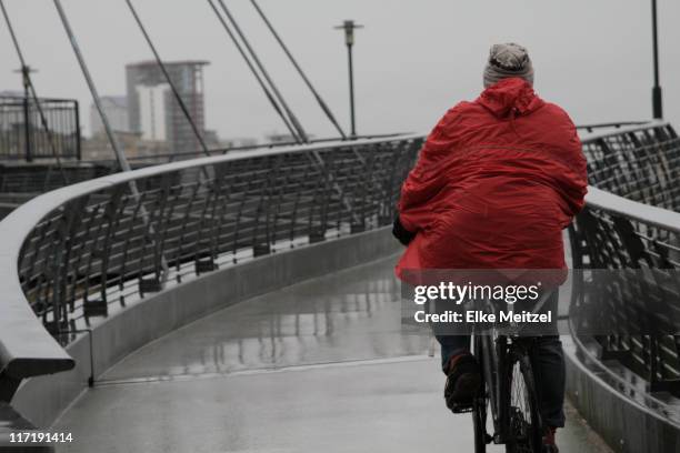 vue arrière de l'homme avec imperméable de cyclisme - vêtement de pluie photos et images de collection