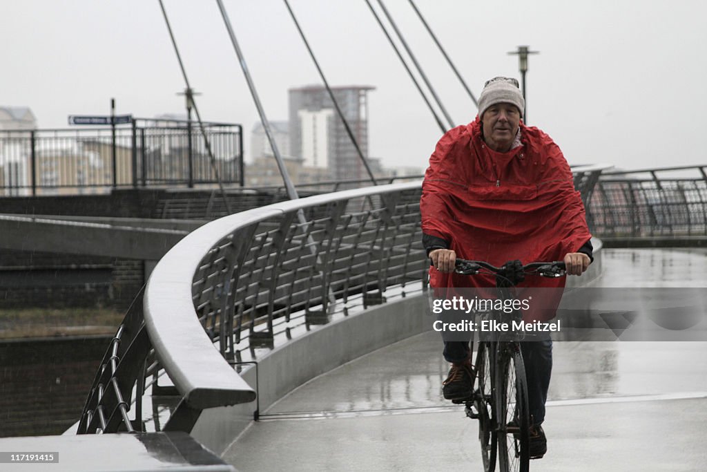 Mann mit Regenmantel-Radfahren