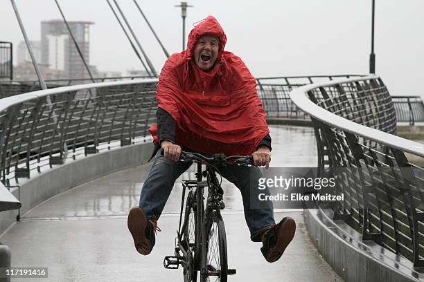 男性に雨でのサイクリングお楽しみください。 - ポンチョ ストックフォトと画像