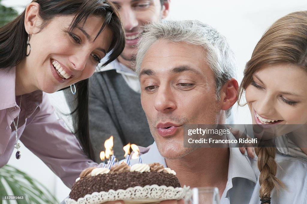 Friends blowing on birthday candles cake