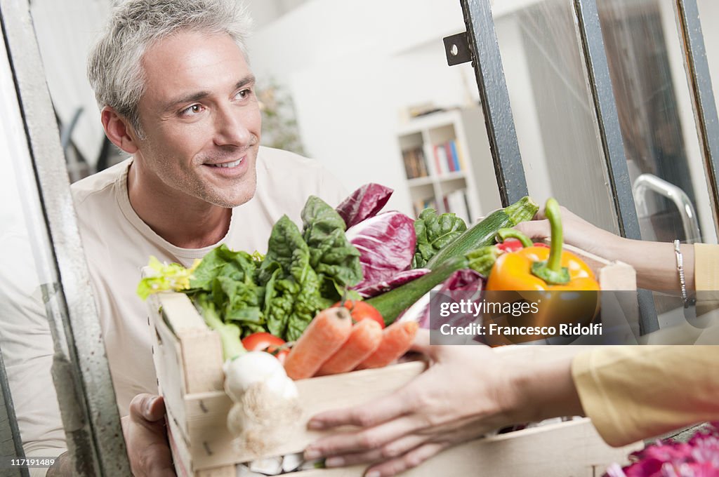 Passing a crate of organic vegetables