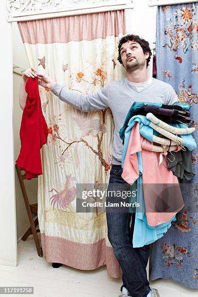 man holding clothes by a changing room - bored girlfriend stock pictures, royalty-free photos & images