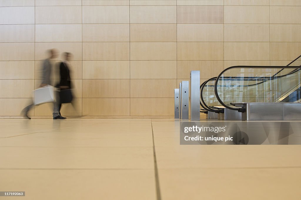 Business people walking towards an escalator