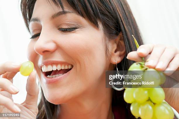 jovem mulher comer cacho de uvas - uva imagens e fotografias de stock