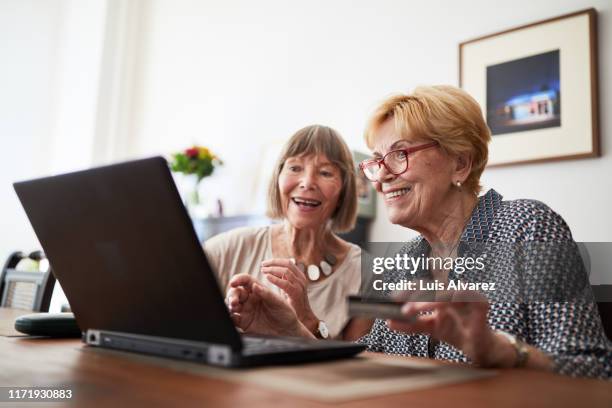 senior women friends doing online shopping - credit union fotografías e imágenes de stock