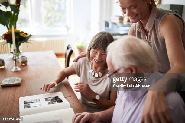 family looking at photos in album - mother daughter senior stock-fotos und bilder