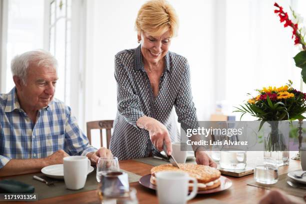 senior woman serving pie to friends - man eating pie stock pictures, royalty-free photos & images