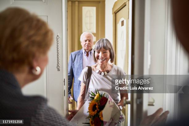 senior couple visiting friends house - visit stock-fotos und bilder