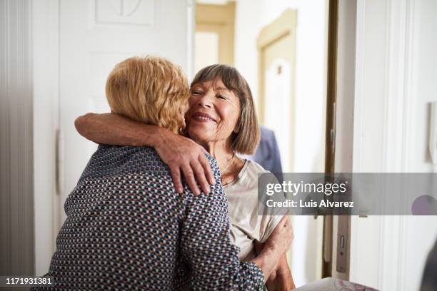 senior couple visiting friends in their home - hug only women stockfoto's en -beelden