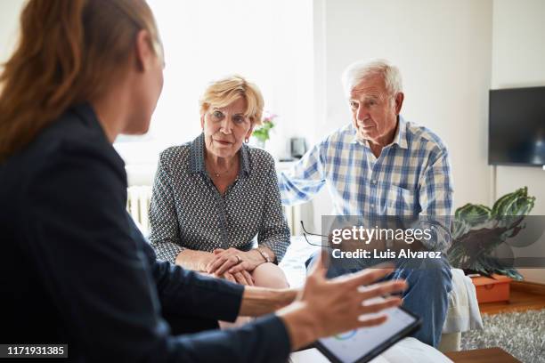 elderly couple at home in meeting with financial advisor - advice home stock-fotos und bilder