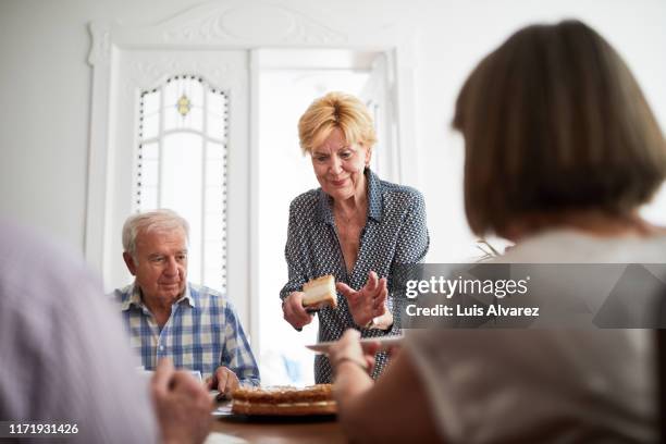 elderly woman serving guest during a meal - man eating pie stock-fotos und bilder