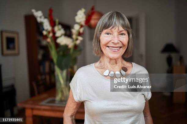 portrait of attractive senior woman at home - frau alt stock-fotos und bilder