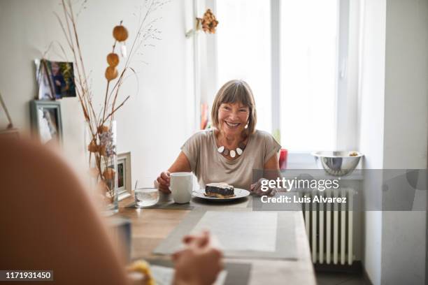 senior woman having breakfast with daughter in kitchen - morning tea stockfoto's en -beelden