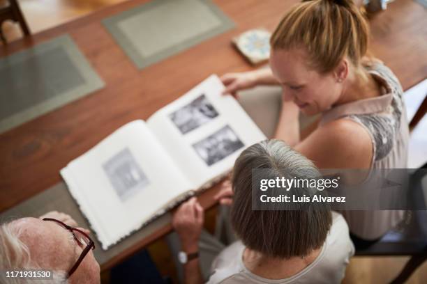 family looking old photo album together - mother daughter senior stock-fotos und bilder