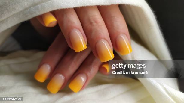 close-up of woman fingers with nail art manicure in yellow colour - ombre stock-fotos und bilder