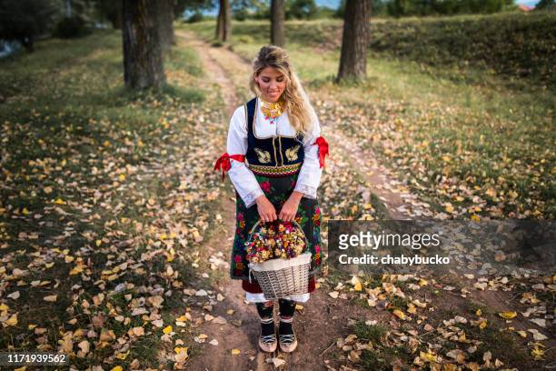 happy young woman in traditional clothing holding flowers - serbia tradition stock pictures, royalty-free photos & images