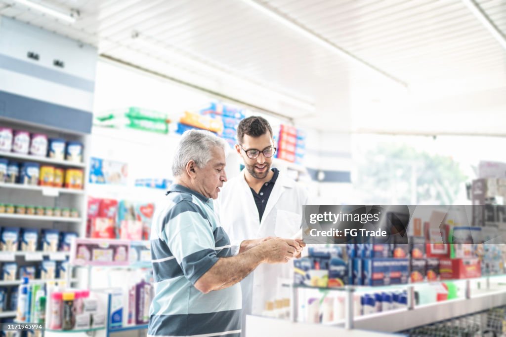 Young pharmacist helping a customer finding a medicine