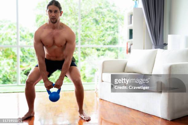 man using the kettle bell to exercise in the living room. - sporting training and press conference stock pictures, royalty-free photos & images