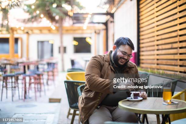 overweight man enjoying alone coffee in sidewalk cafe - coffee on patio stock pictures, royalty-free photos & images