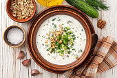 Traditional bulgarian cold summer soup tarator with yogurt, dill, cucumber and walnuts in ceramic bowl on wooden table