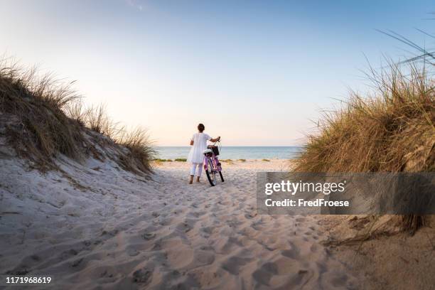 frau mit fahrrad am strand bei sonnenuntergang - beach woman stock-fotos und bilder