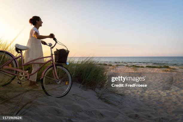 mujer con bicicleta en la playa al atardecer - usedom fotografías e imágenes de stock