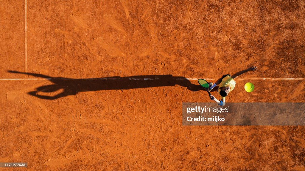 Joueur de tennis sur le service sur la cour de terre battue